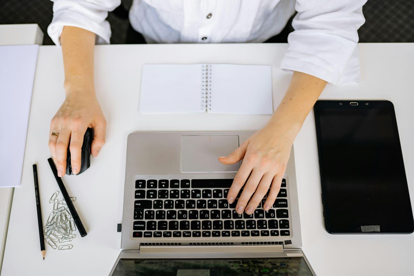 Un dueño de negocio trabajando en una laptop sobre un escritorio blanco y ordenado