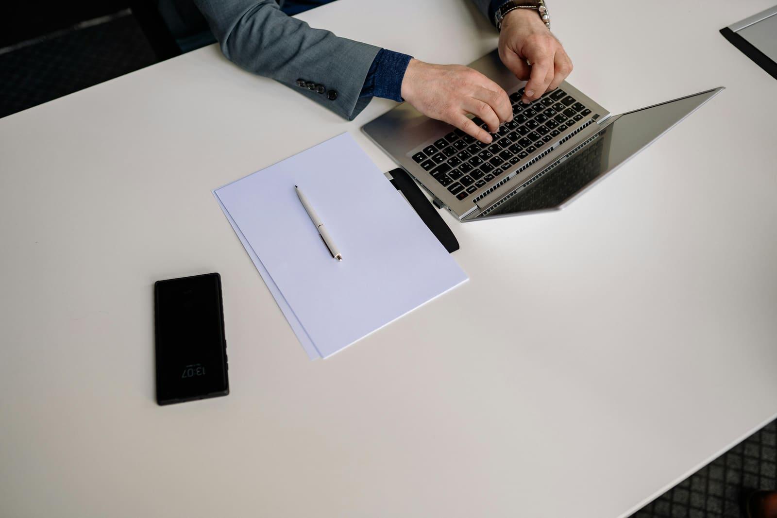 Una persona trabajando en una laptop con una libreta y un bolígrafo