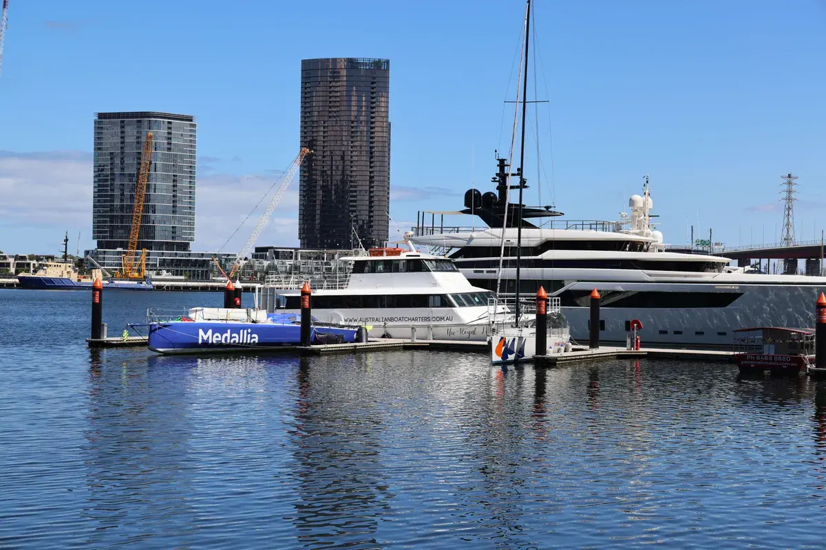 Luxury yachts docked at a marina with a modern city skyline in the background