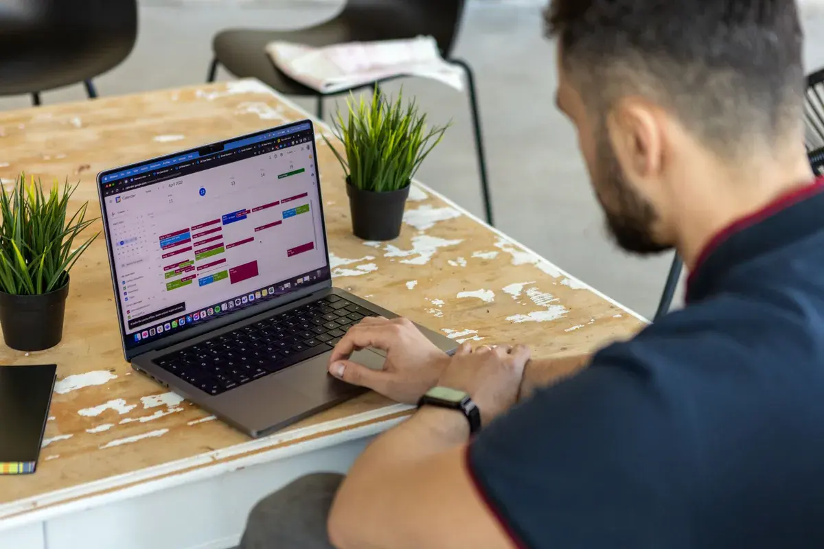 Over the shoulder view of a person reviewing a month calendar on a laptop screen.
