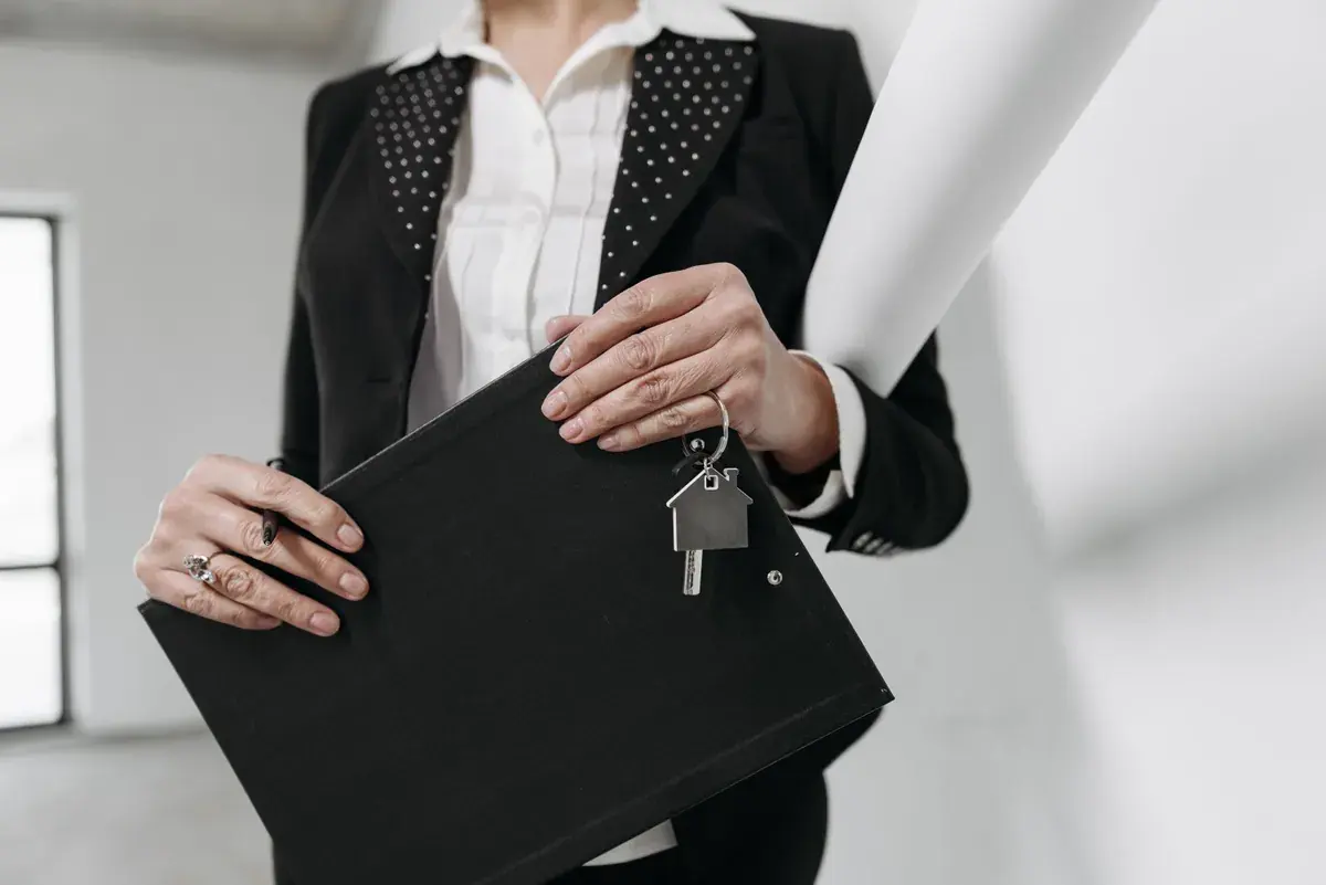A professional holding a black document folder with a house shaped keyring