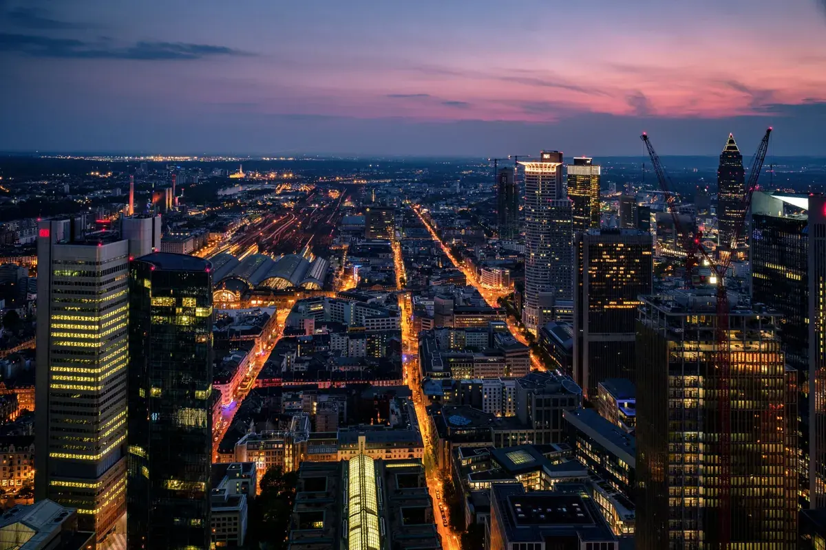 Aerial view of a foreign business district at dusk with lit office towers and streets.