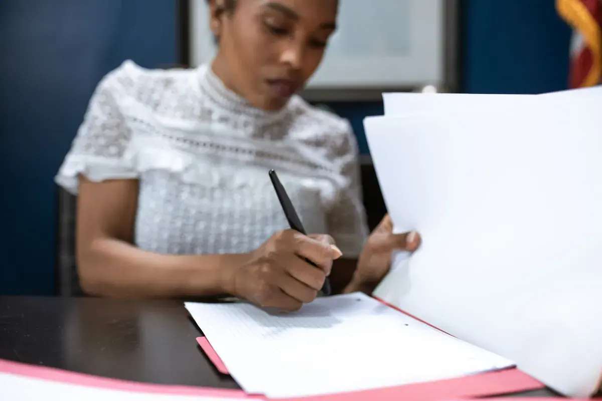 Close-up of a woman writing on a grid ruled page inside an open folder.