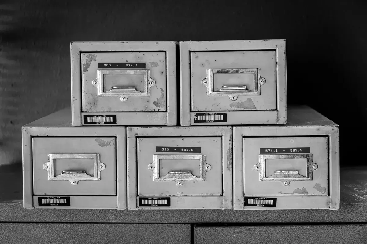 Stacked metal filing cabinet drawers with worn label holders in a quiet office archive