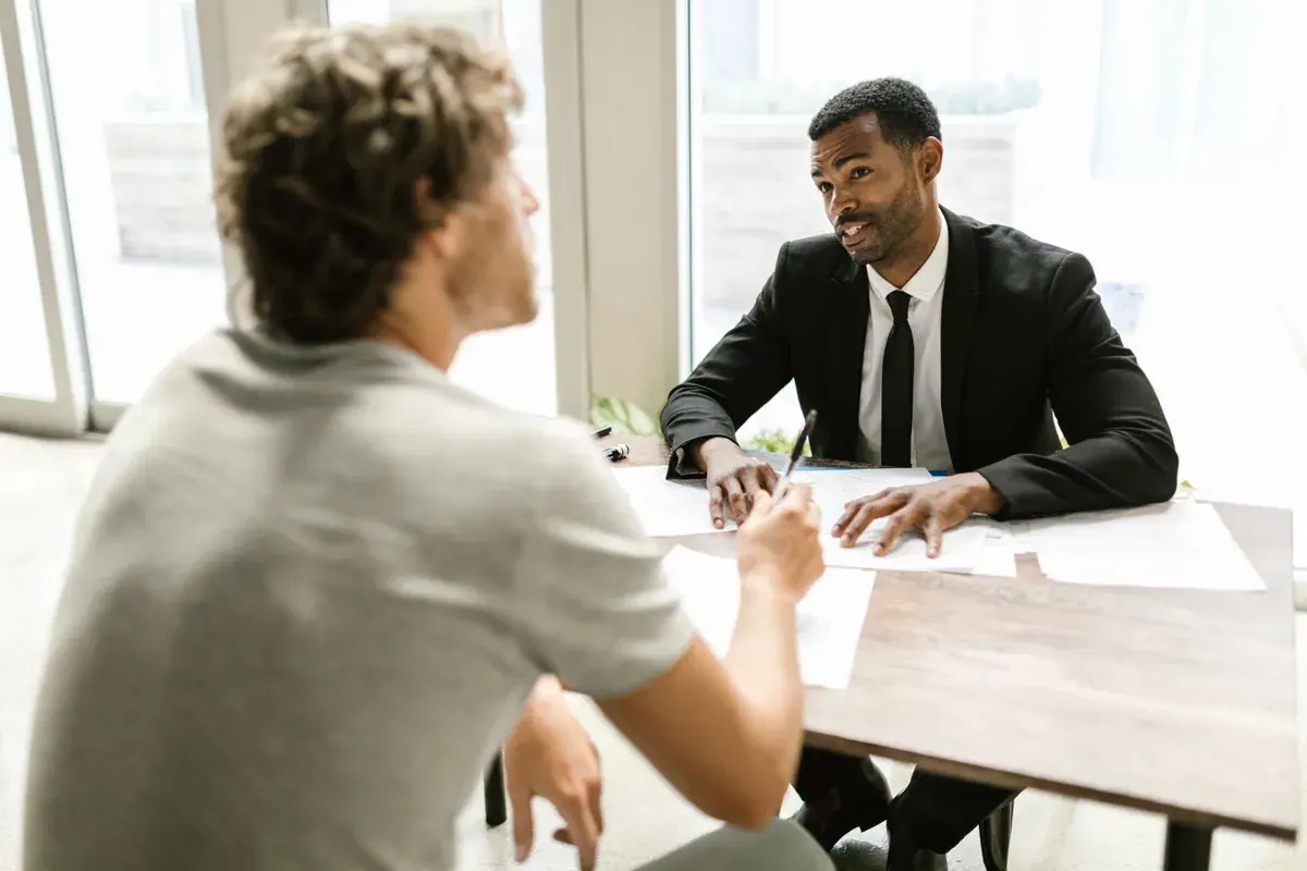 Two people at a modern office table having a discussion over paperwork