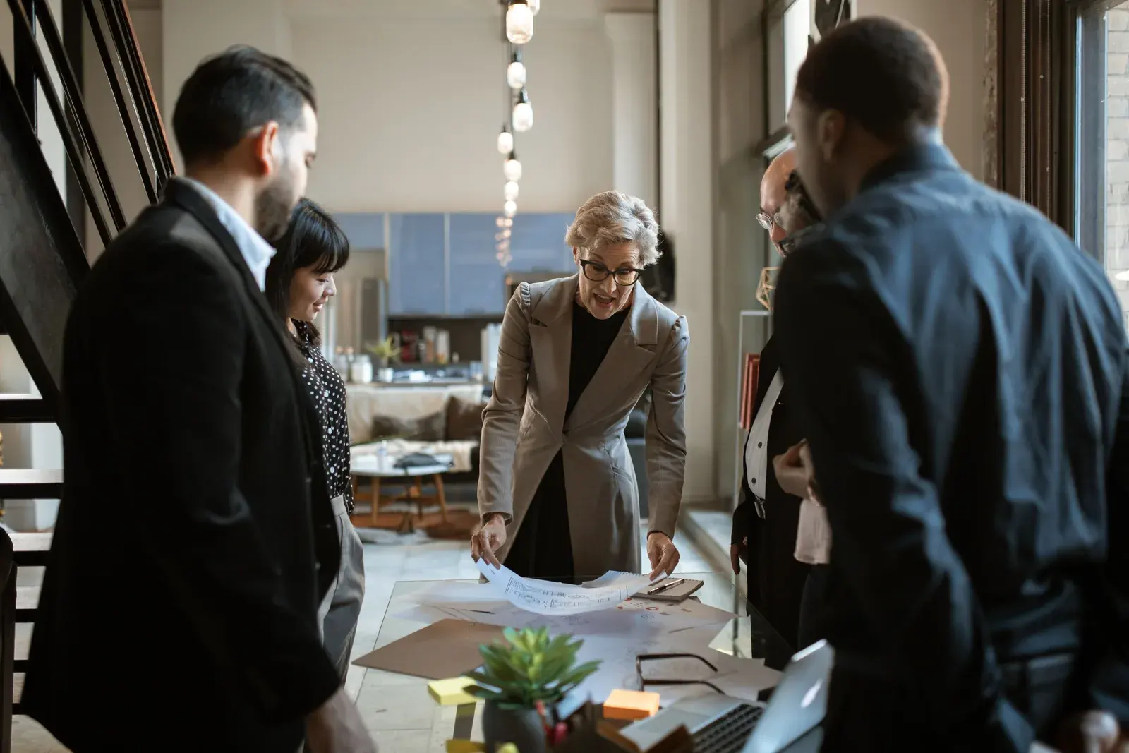 A diverse team gathered around a workspace, reviewing loose paper documents together