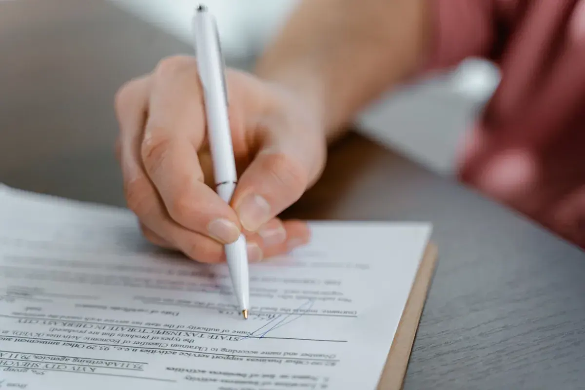 Close-up of a hand signing a printed certification form with a pen