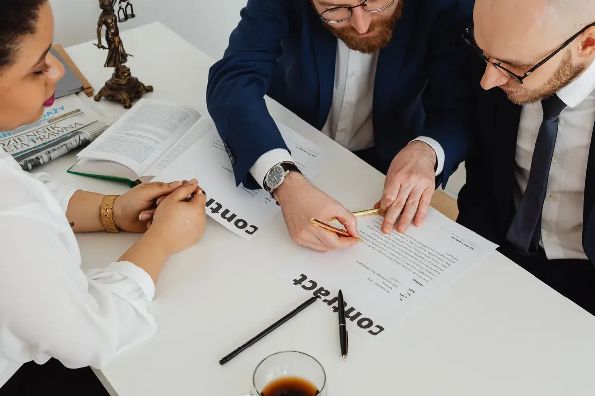Three colleagues leaning over a printed contract on a white office table