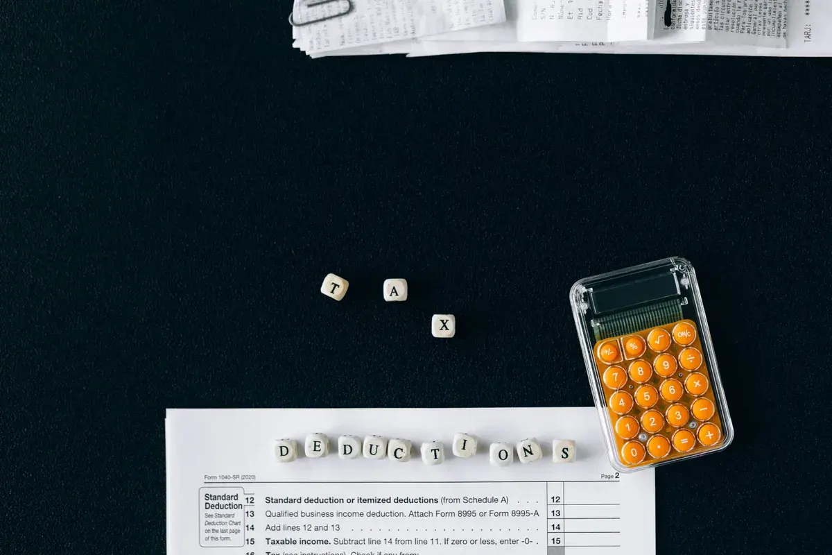 Top-down view of tax documents and a calculator on a dark desk surface