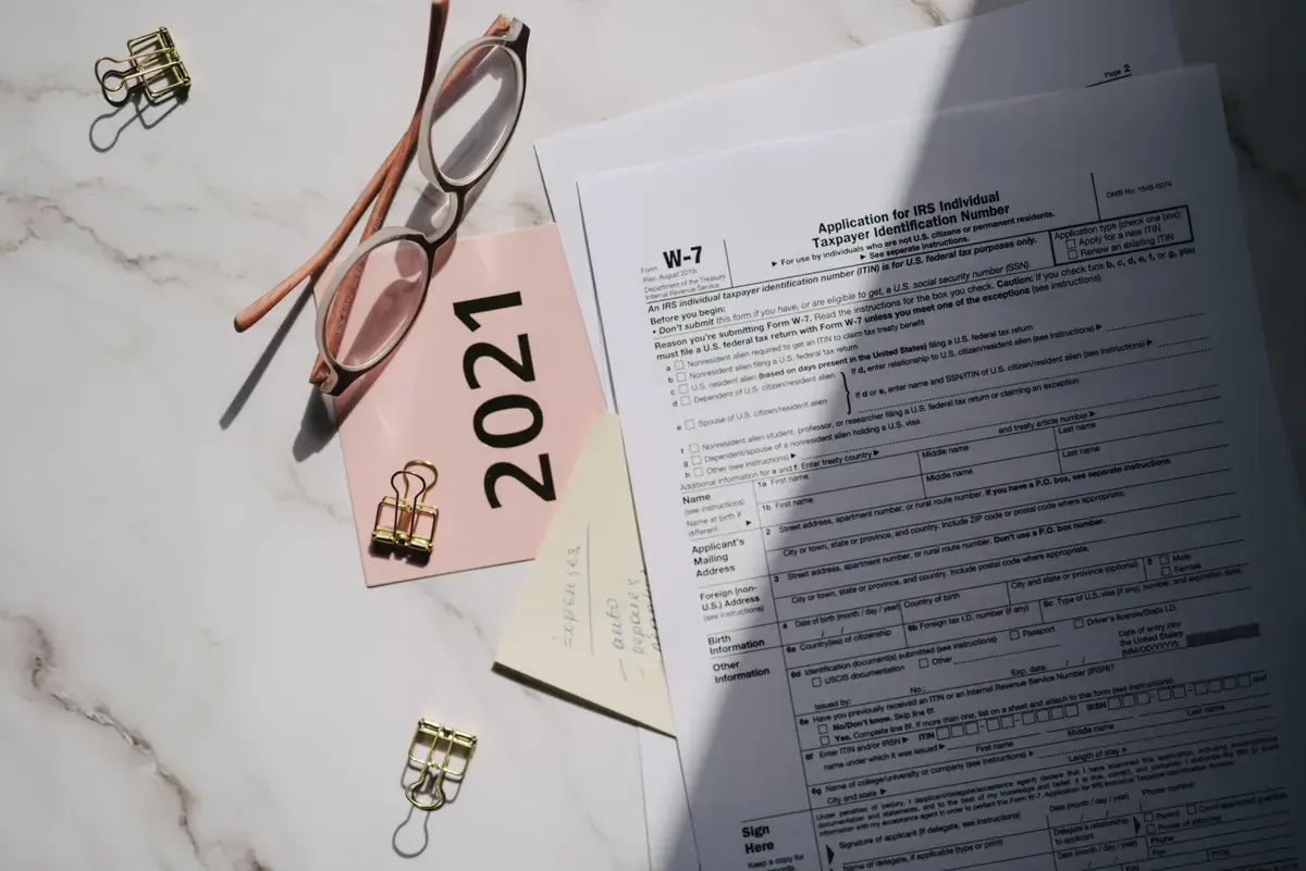 Flat lay of IRS tax forms with reading glasses on a marble surface