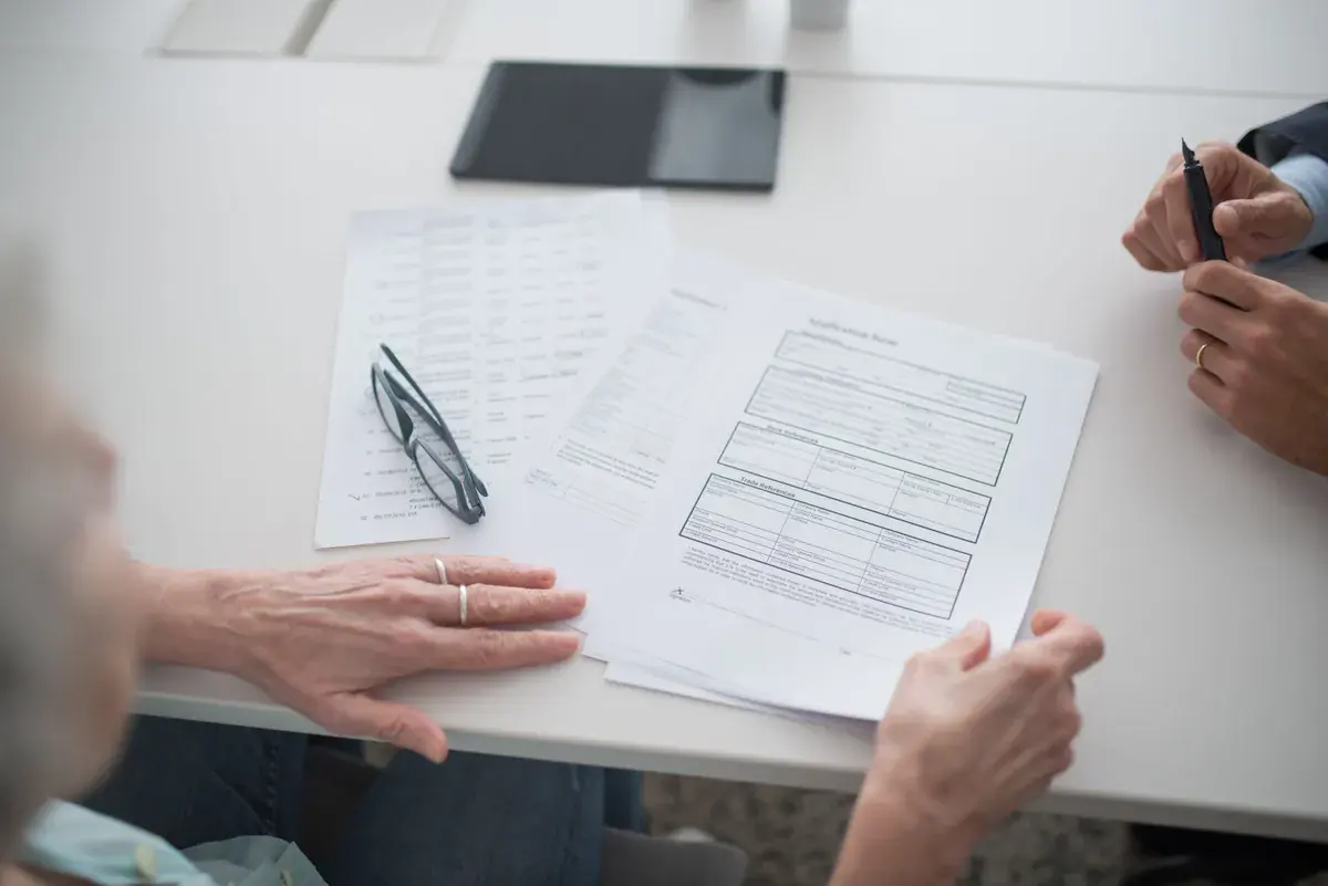 Overhead view of two people at a white table reviewing a blank application form