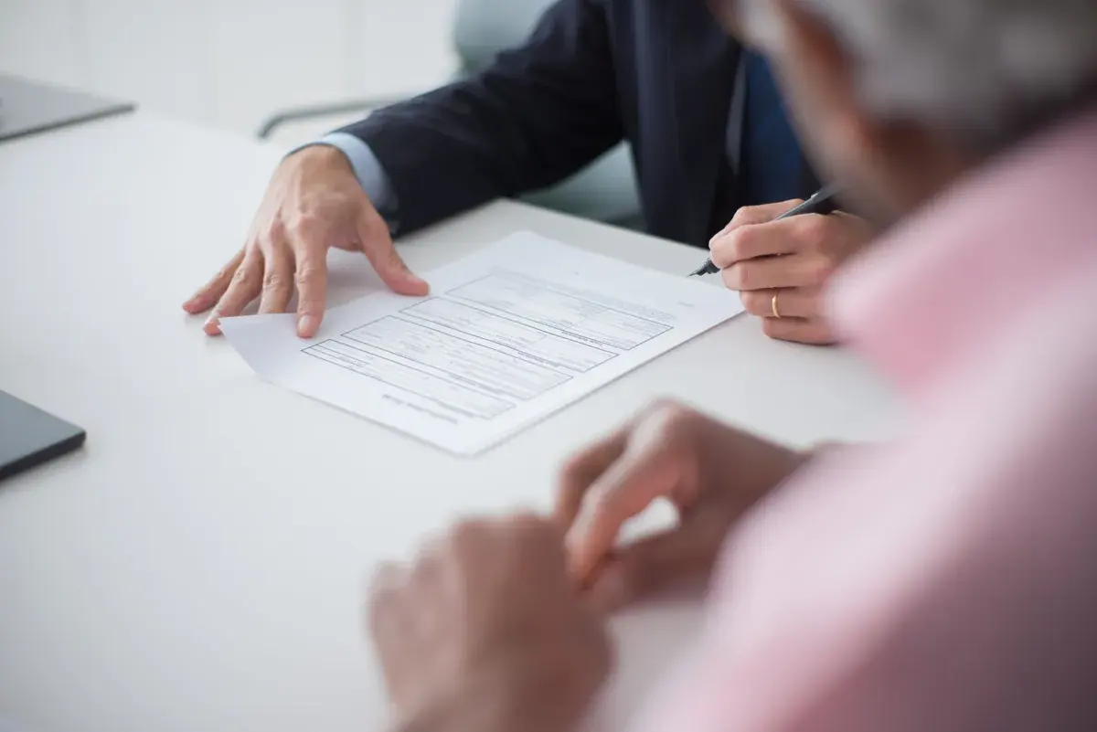 Dos personas sentadas en un escritorio revisando juntas un formulario impreso