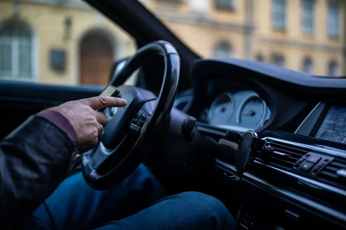 A driver's hands on a steering wheel while moving through a city street