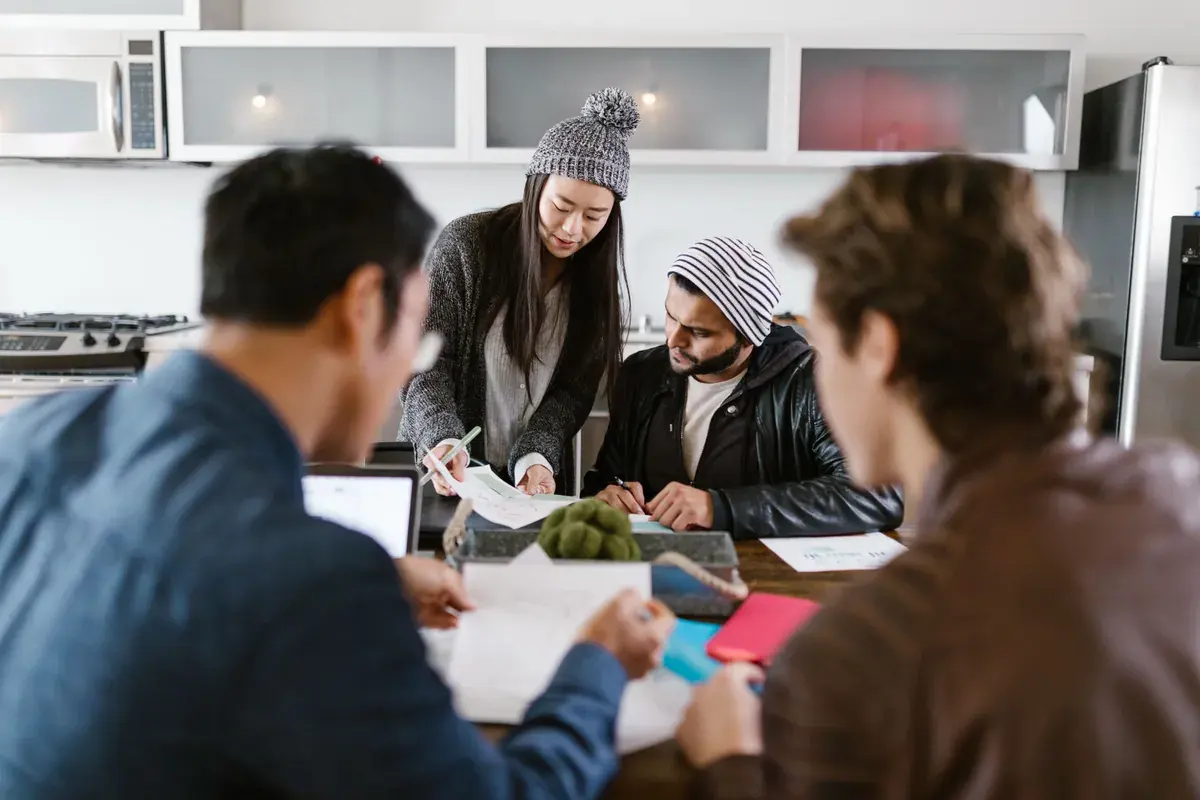 A group of young entrepreneurs collaborating around a brightly lit meeting room table