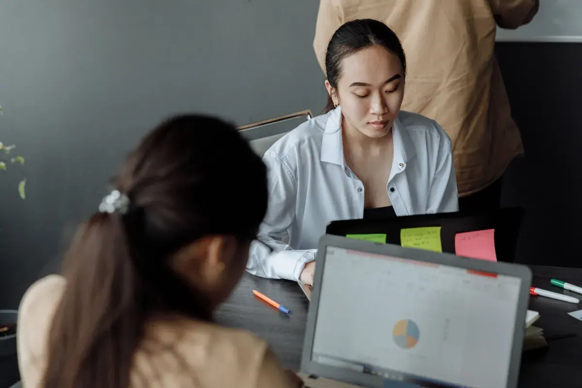 Young professionals reviewing printed documents next to open laptops at a wooden conference table