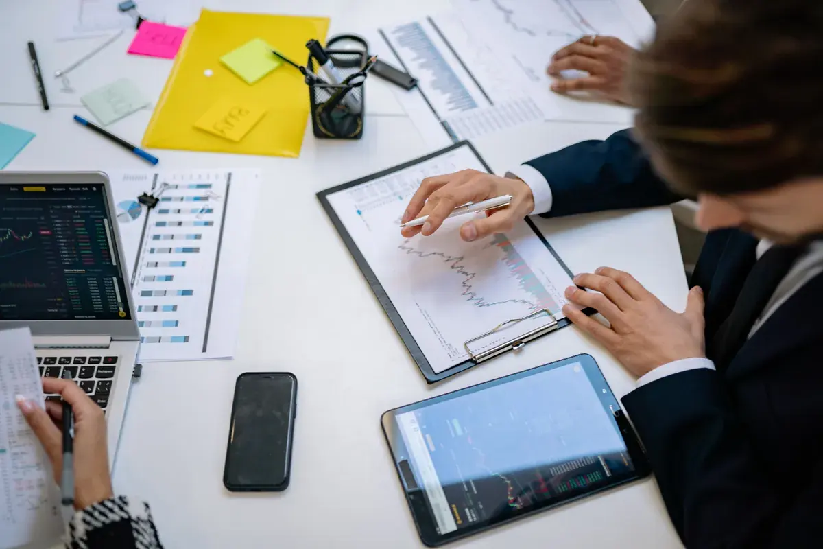 A team around a bright conference table examining financial charts on tablets and printed sheets