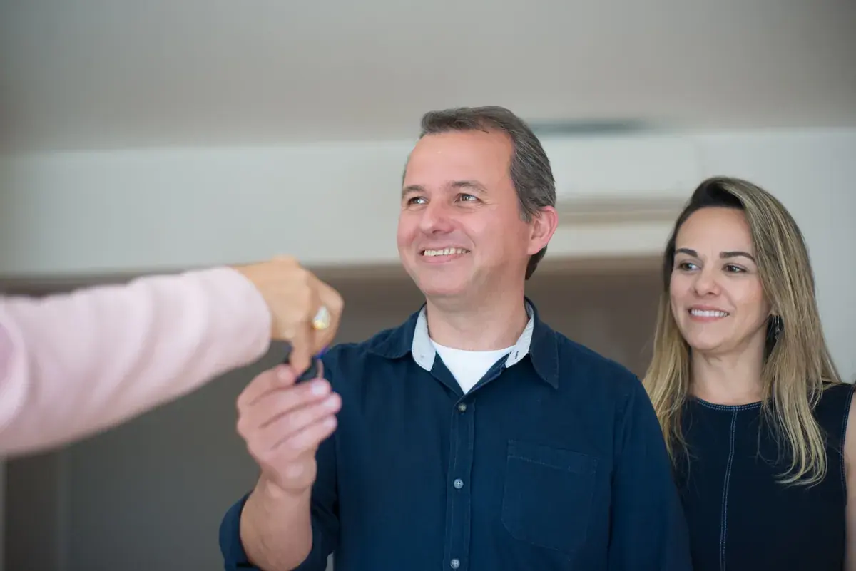 Two people at a table receiving a set of house keys after finalizing paperwork