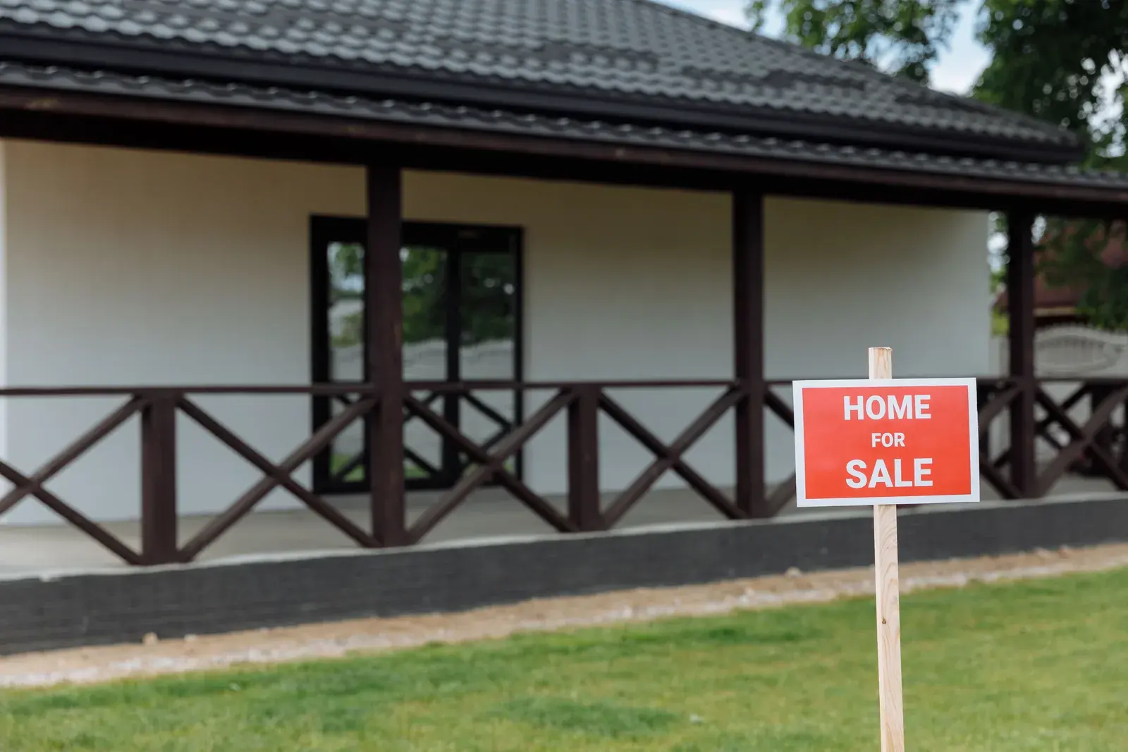 A single-family house with a front porch and a For Sale sign on the front lawn
