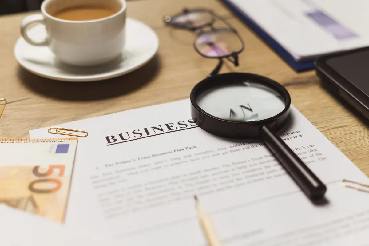 Un espacio de trabajo tranquilo con una laptop, documentos impresos y una taza de café dispuestos para una sesión de trabajo