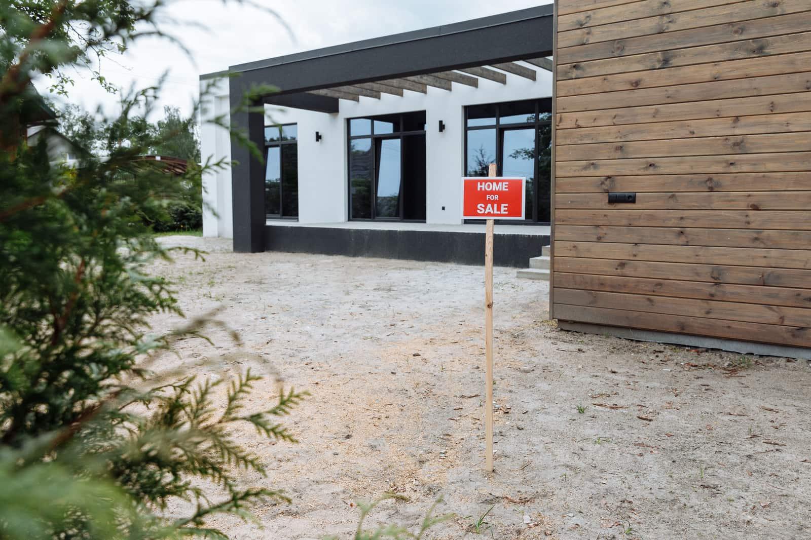A modern home with a for-sale sign in the front yard