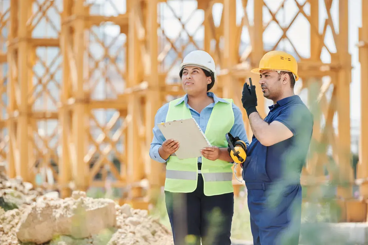 Construction workers in hard hats and reflective gear discussing plans at an outdoor jobsite