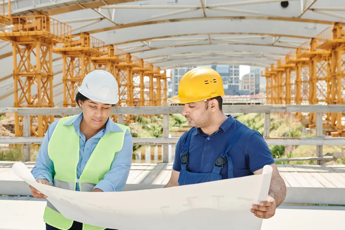 A construction team reviewing printed blueprints together at an outdoor project site