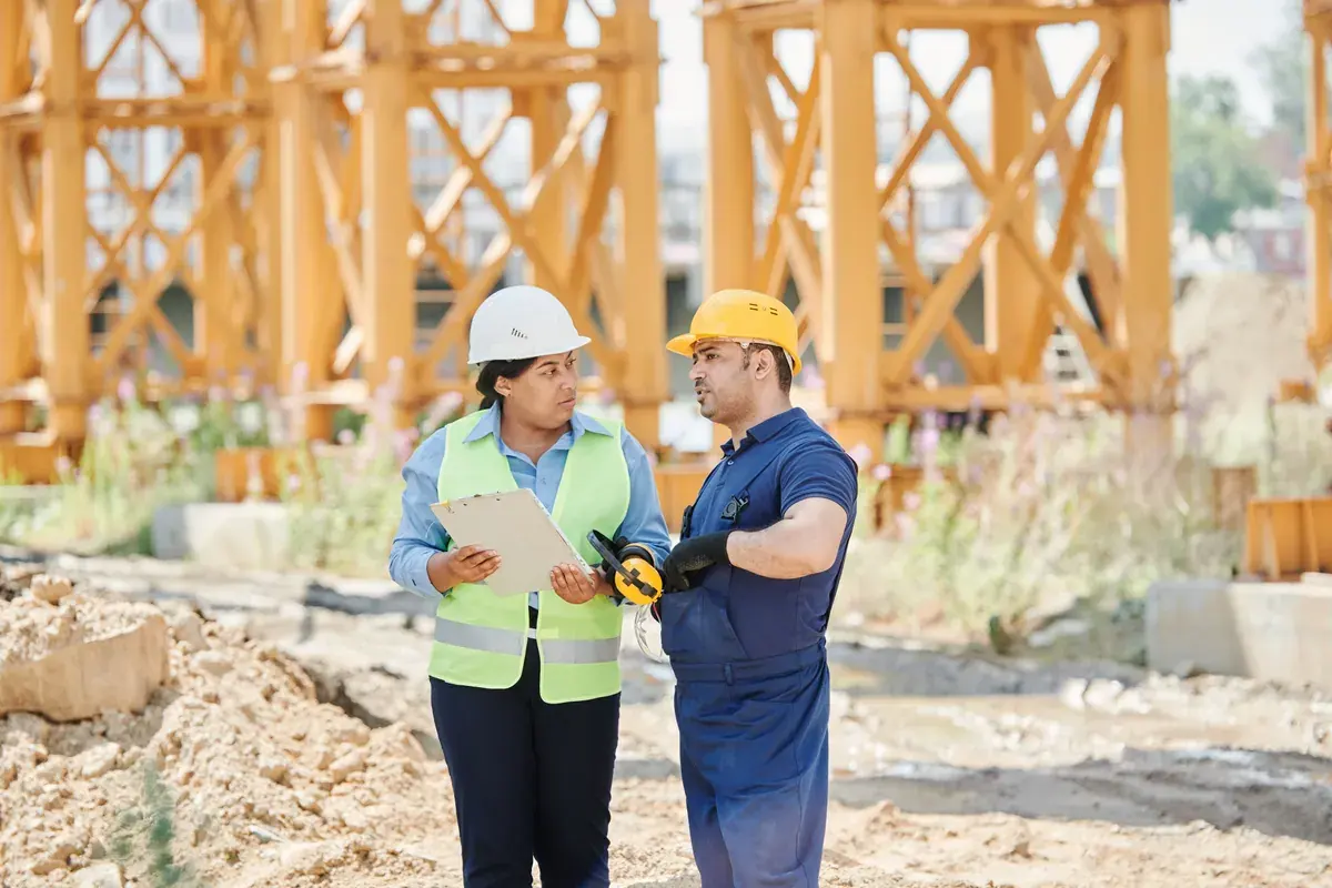 Construction workers in safety gear in conversation at an active jobsite