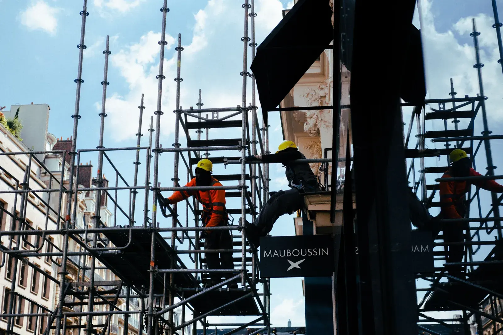 Silhouetted workers on scaffolding during a construction project under an open sky