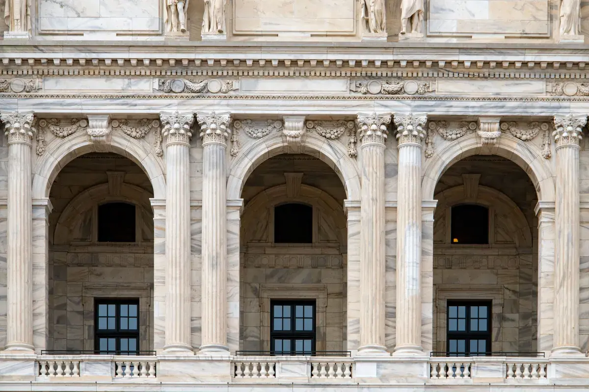 Marble arches and carved columns across the upper facade of a neoclassical government building