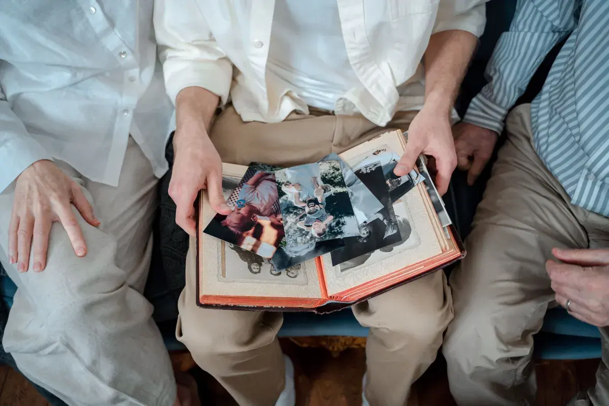 An older couple hold an open photo album across their laps
