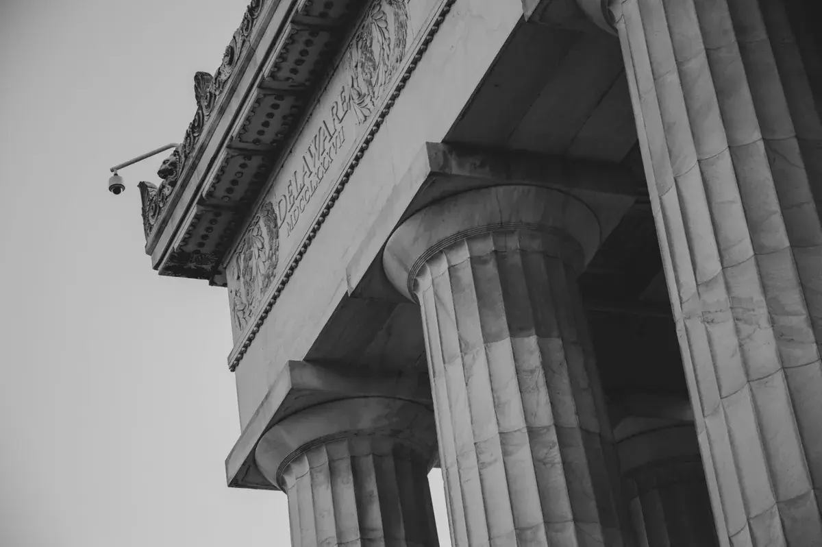 Monochrome low angle view of marble columns and carved stone detail on a federal building.