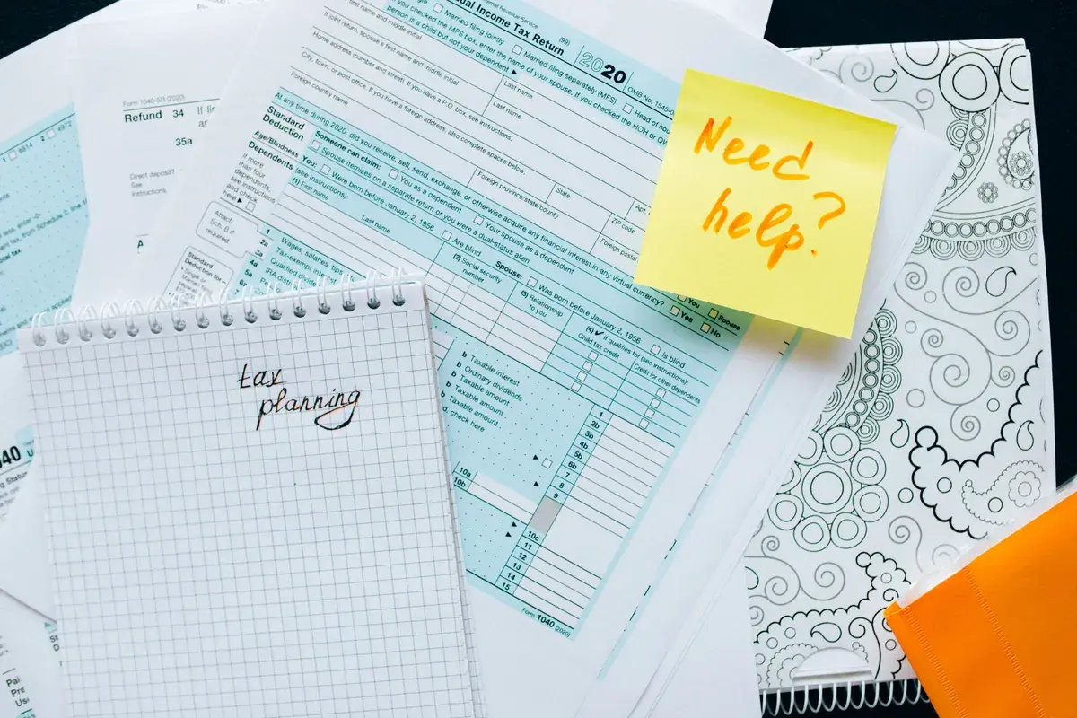 Neatly arranged tax documents and a handwritten note laid out on a light wooden desk
