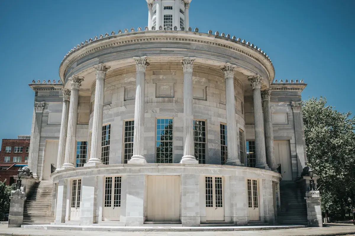 A neoclassical federal-style building with tall marble columns against a clear blue sky