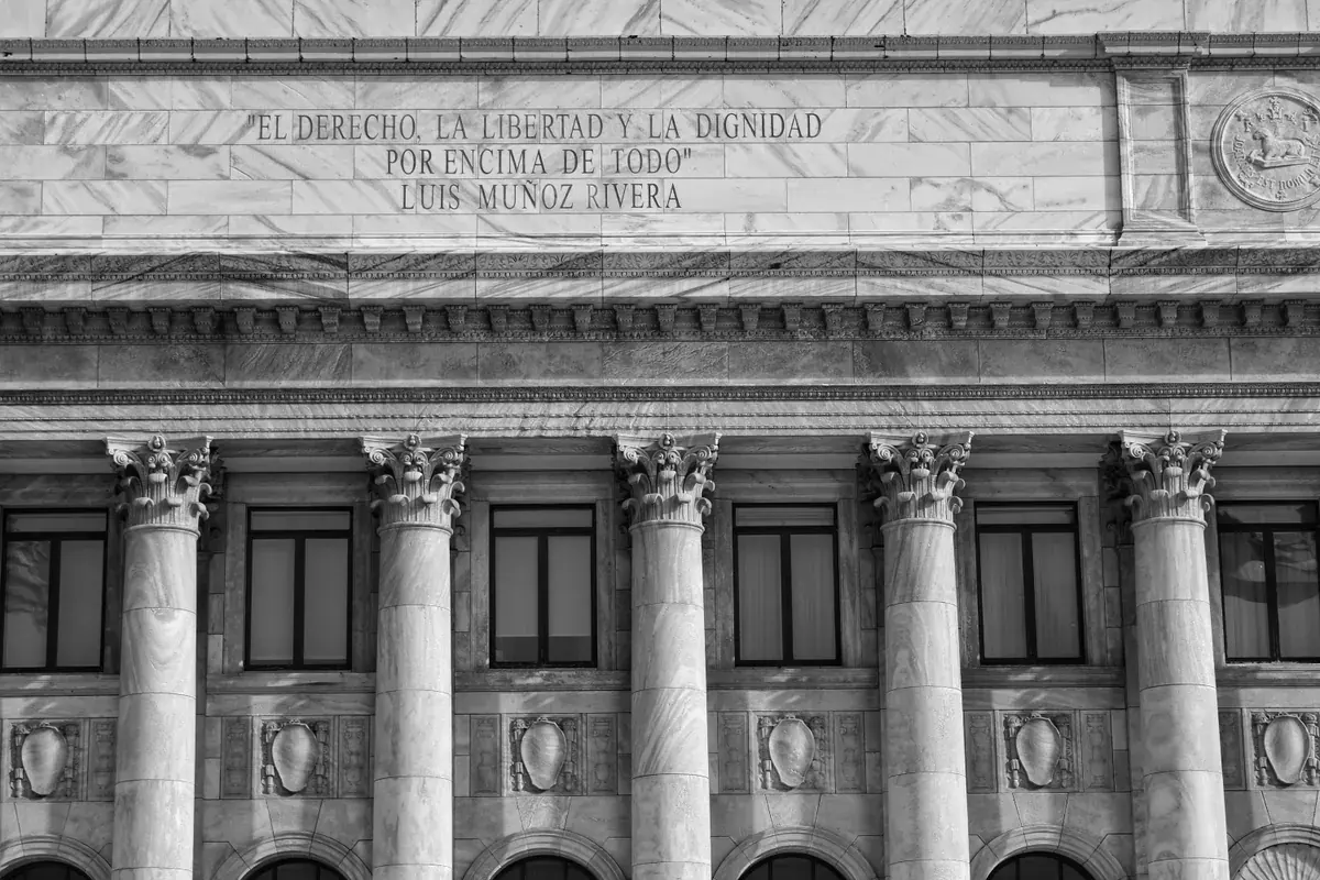 A stately government building facade carved from marble with Corinthian columns and a civic inscription above