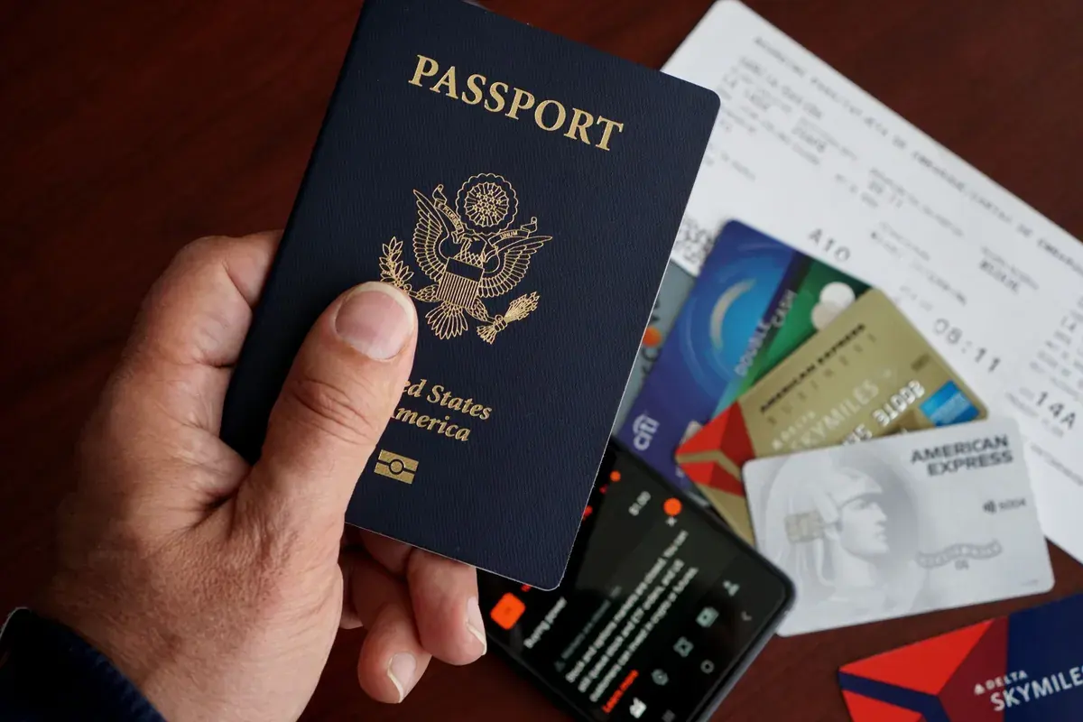 A U.S. passport, credit cards, and a mobile phone laid out on a wooden table