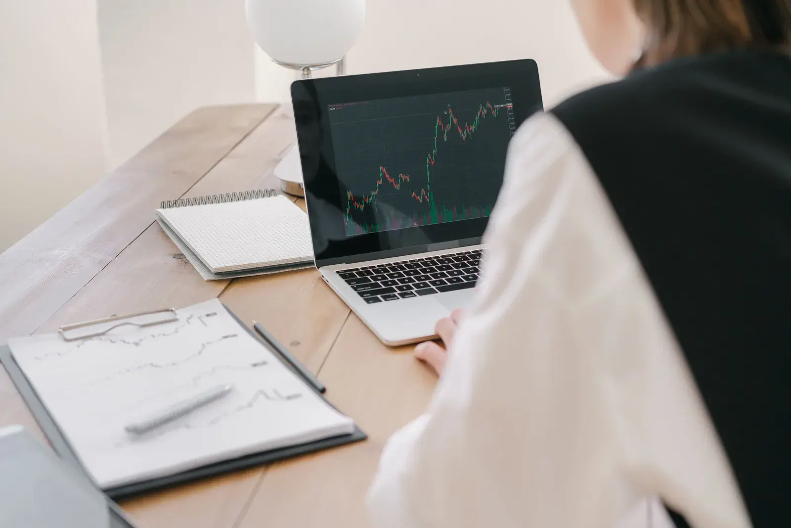 Vista sobre el hombro de una persona que estudia un gráfico de mercado en alza en la pantalla de su computadora portátil