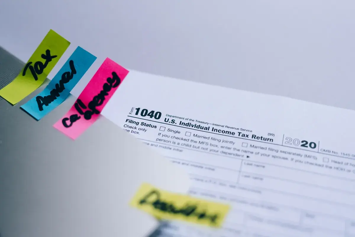 Primer plano de un Formulario 1040 en blanco con notas adhesivas escritas a mano en el borde