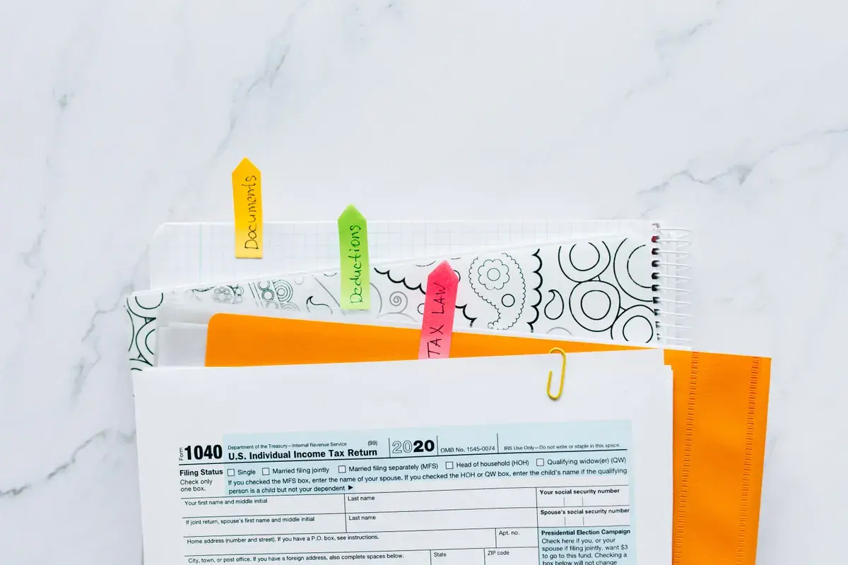 Tax papers in a folder marked with handwritten color tabs on a marble desk