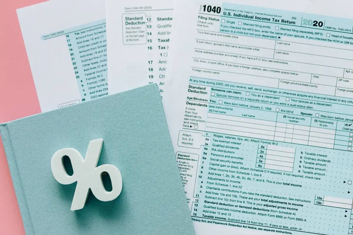 Printed federal tax return pages beside a white percent symbol on a pastel desk