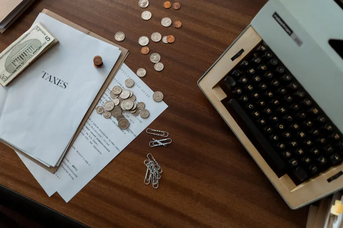 Overhead view of a wooden desk with printed pages, scattered coins, paper clips and a vintage typewriter