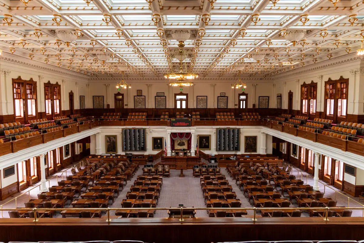 Rows of empty desks and seats inside an ornate legislative chamber