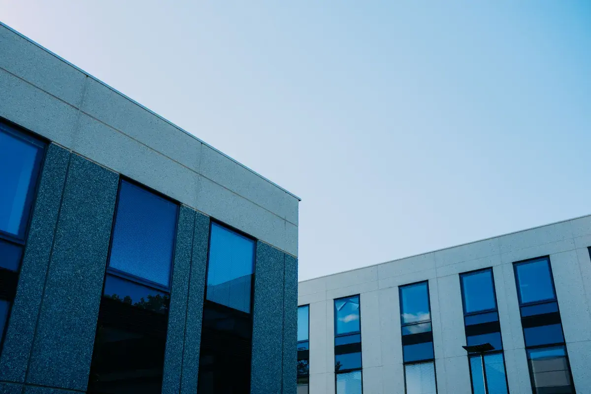 Two low-rise office buildings with reflective windows meeting at a clean architectural corner