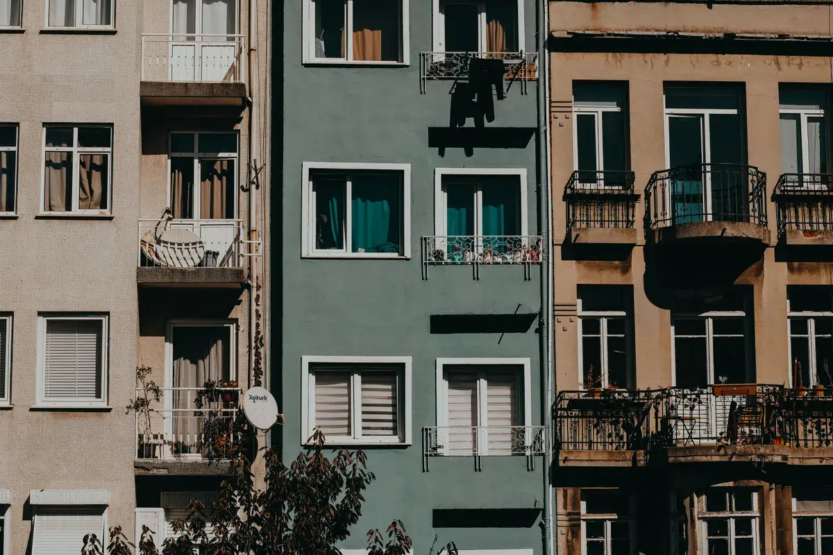 A row of older city apartment buildings with varied facades and small balconies
