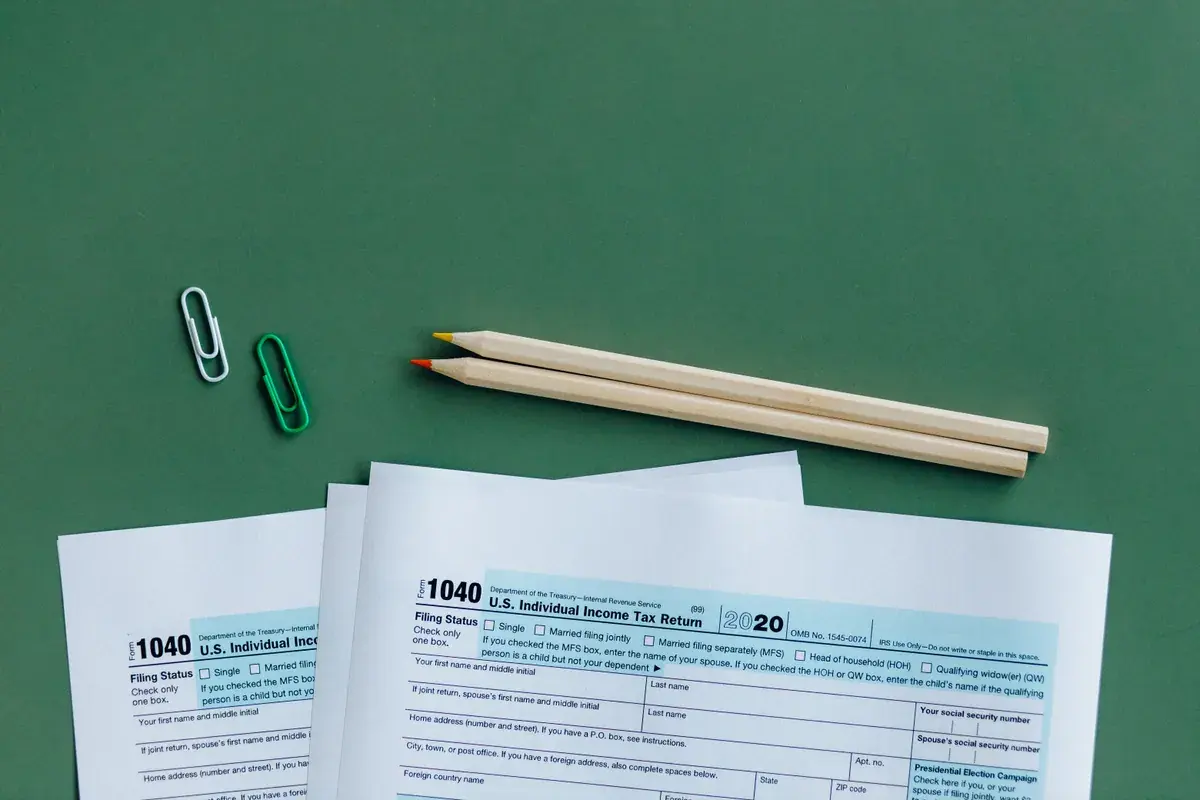 Blank federal income tax return pages laid out with pencils on a green desk