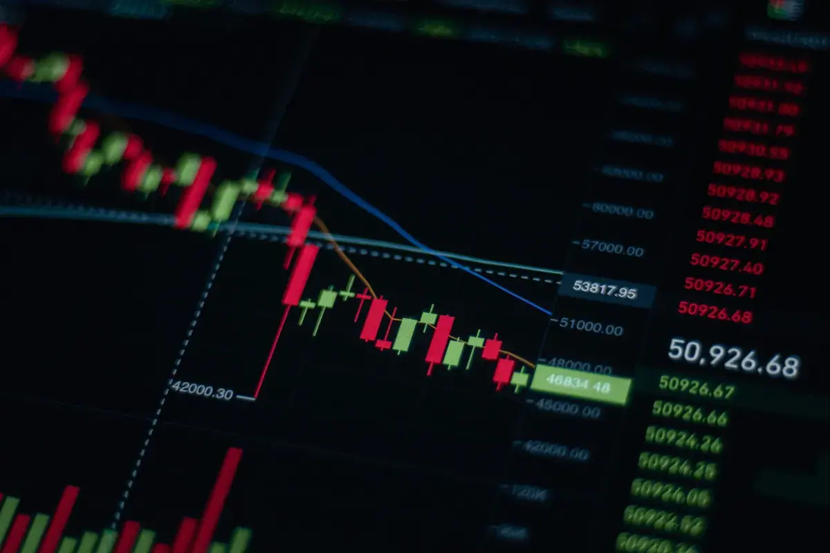 Close view of a candlestick price chart and a column of quotes on a dark screen