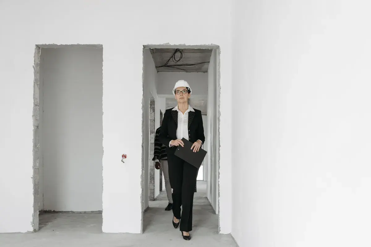 Person in a hard hat walking with a folder through an unfinished interior