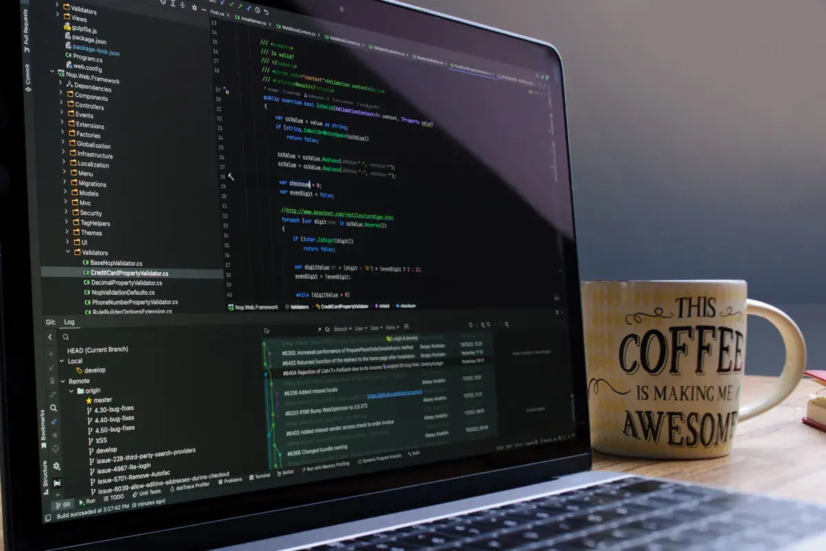 A close-up of a laptop with programming code beside a coffee mug on a wooden desk
