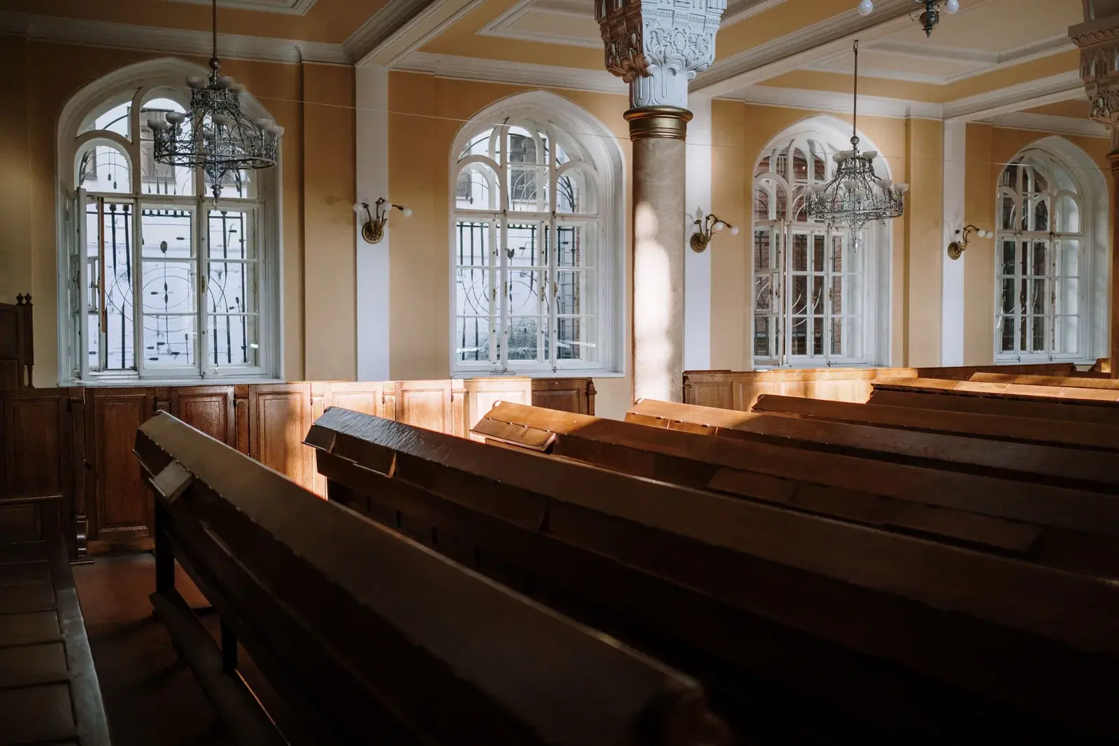 La luz del sol cae sobre bancas de madera vacías dentro de una iglesia tranquila