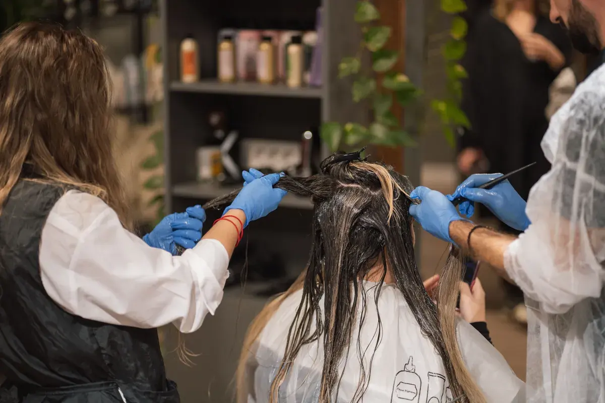 Two salon stylists working together on a client's hair color