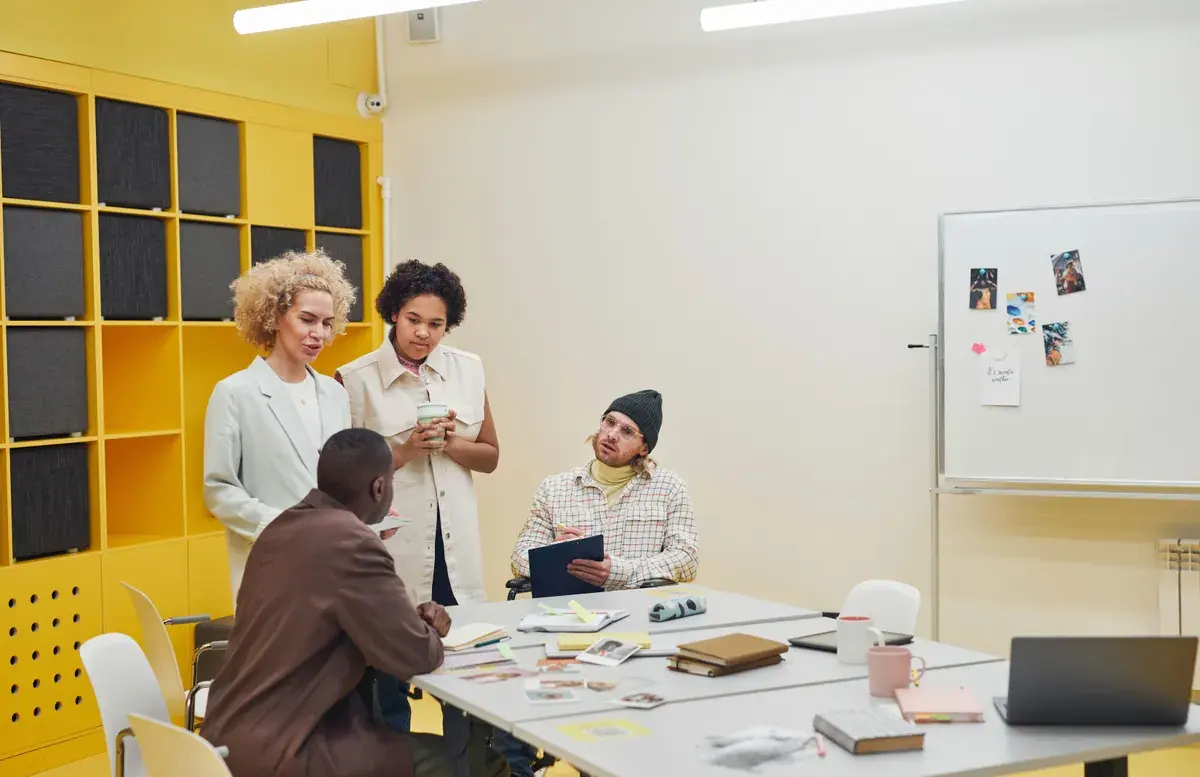 A diverse group of professionals seated at a long table reviewing documents during an office meeting